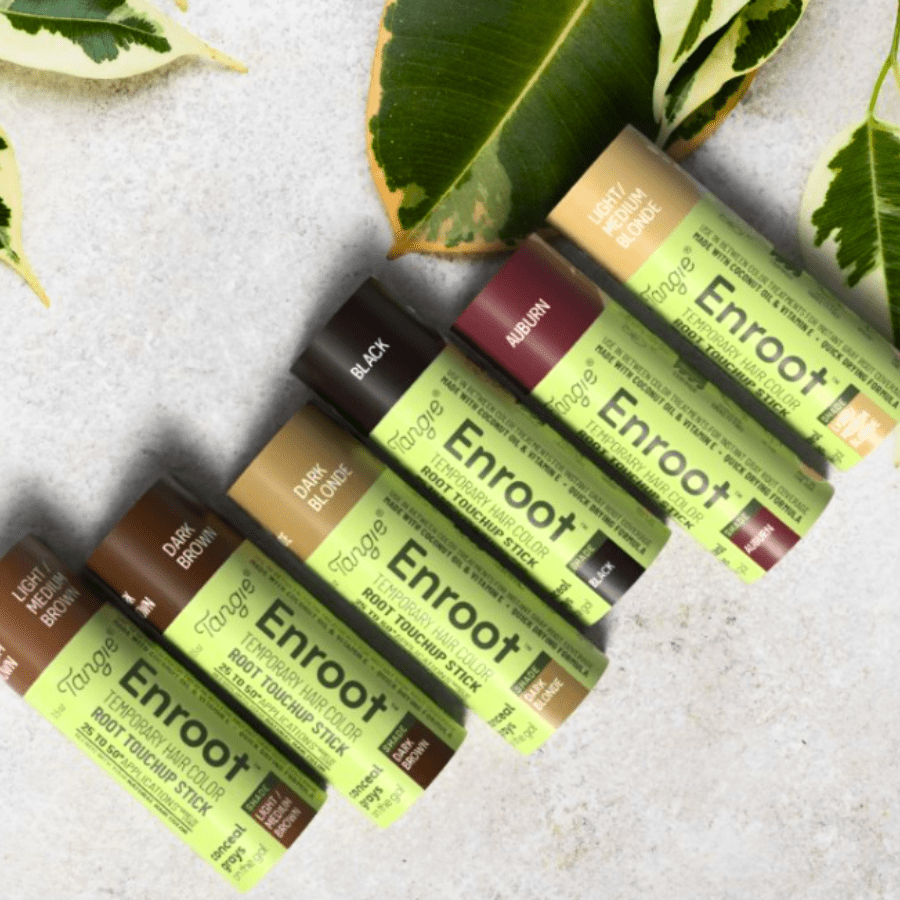 Enroot Temporary Root Touchup Stick tubes in all six shades, arranged in a row on a neutral surface with fresh greenery, highlighting the eco-friendly packaging.