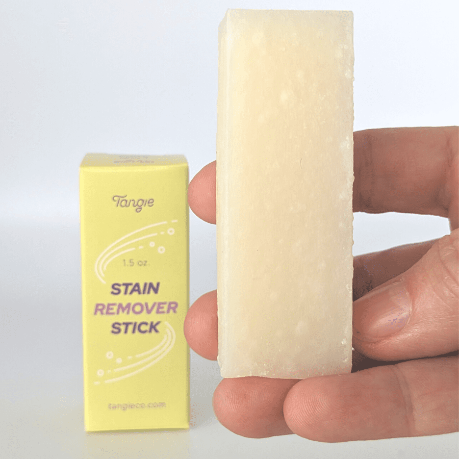 Tangie stain stick in hand with product box in the background of the photo