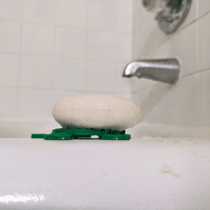 Tangie Turtle Drying Disk with shampoo bar on bathtub ledge showing airflow design