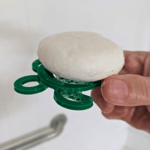 Tangie Turtle Drying Disk held in hand with shampoo bar showing size and portability