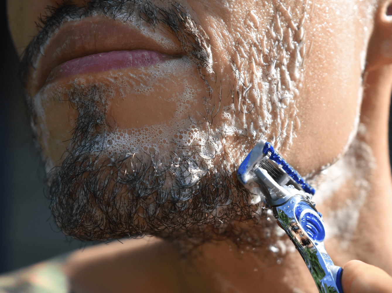 Man shaving with razor using Tangie shave cream soap for a smooth and natural shave.