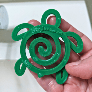 Tangie Turtle Drying Disk held in wet hand showing water-resistant PLA material