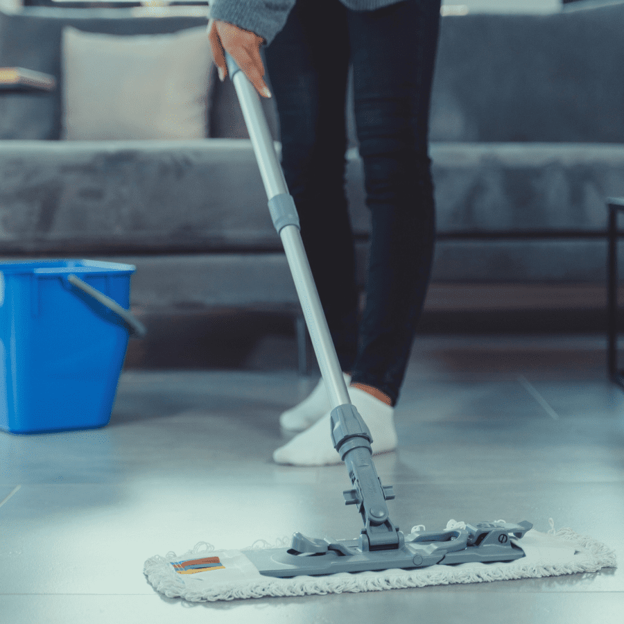 Person mopping floor with cleaning bucket nearby using Tangie Floor Cleaner solution