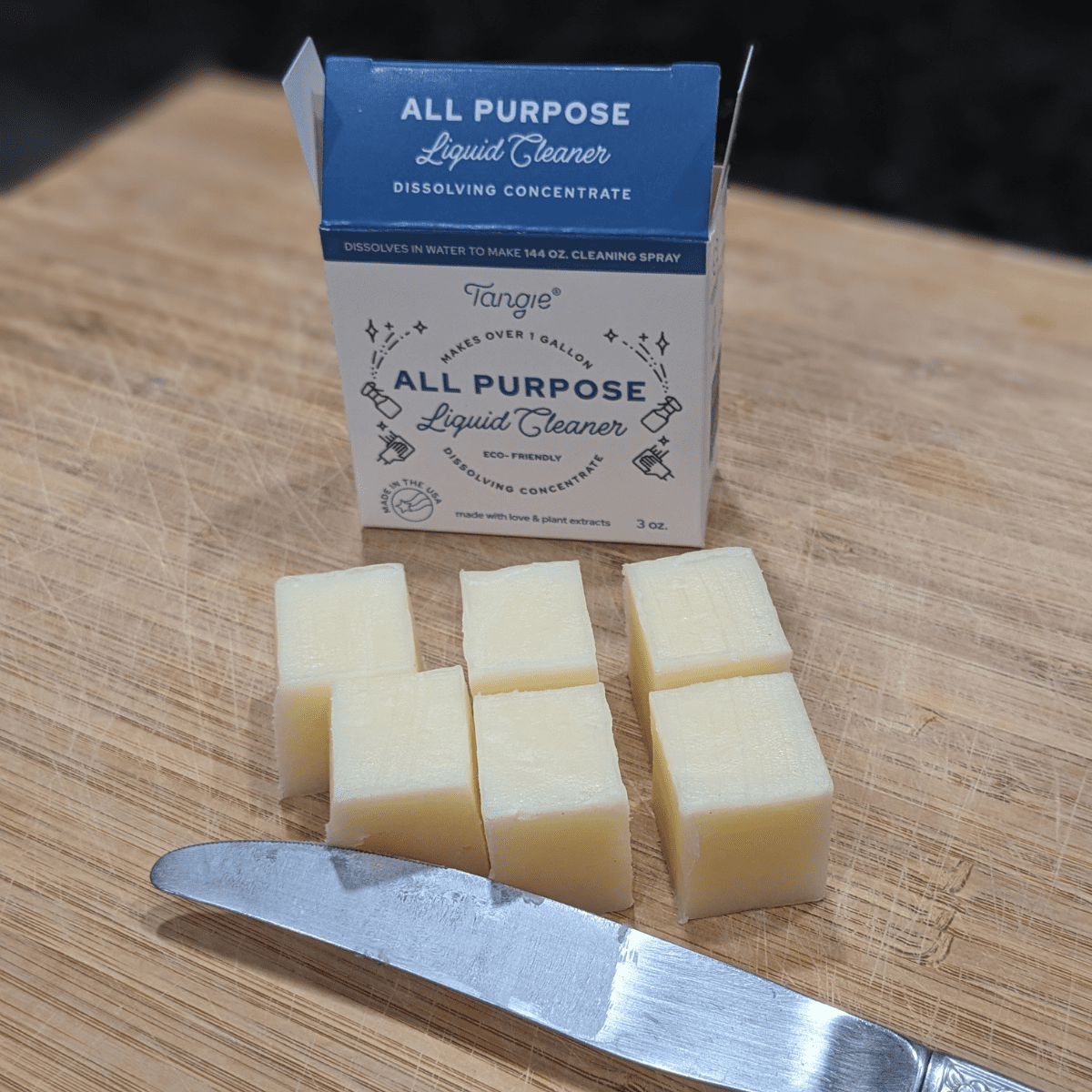 Tangie all-purpose cleaner concentrate bar cut into six pieces on a wooden cutting board with a knife.
